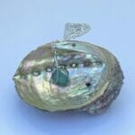 Aqua sea glass necklace displayed on abalone