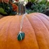 Dark teal heart sea glass necklace on pumpkin