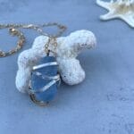 Light blue gold and silver sea glass necklace on coral